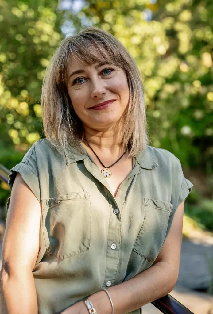 blonde woman in a green shirt seated outside in a garden